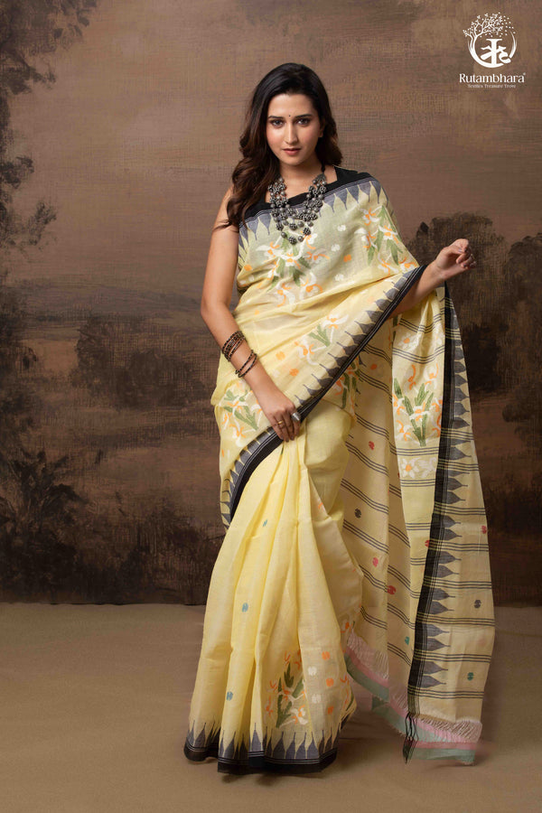 Woman wearing a light yellow saree with a dark border against a brown background