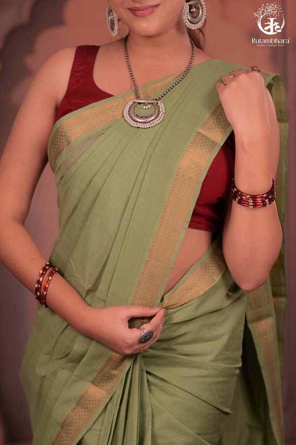Woman wearing a green saree with a red blouse, posing against a neutral background.
