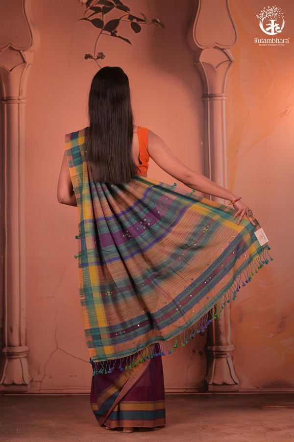Woman wearing a colorful saree with a traditional setting.