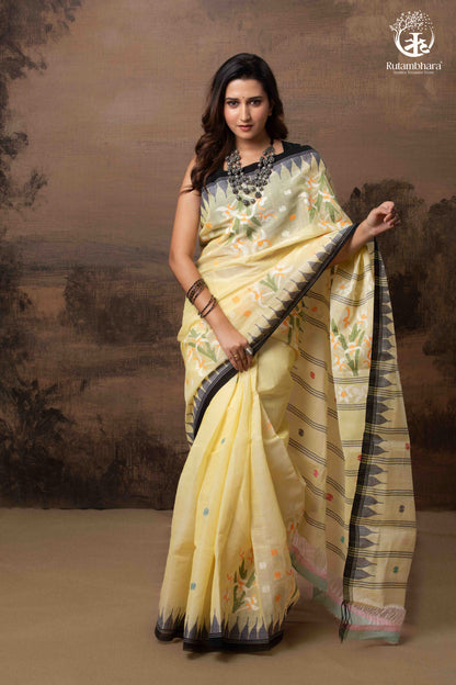 Woman wearing a light yellow saree with a dark border against a brown background
