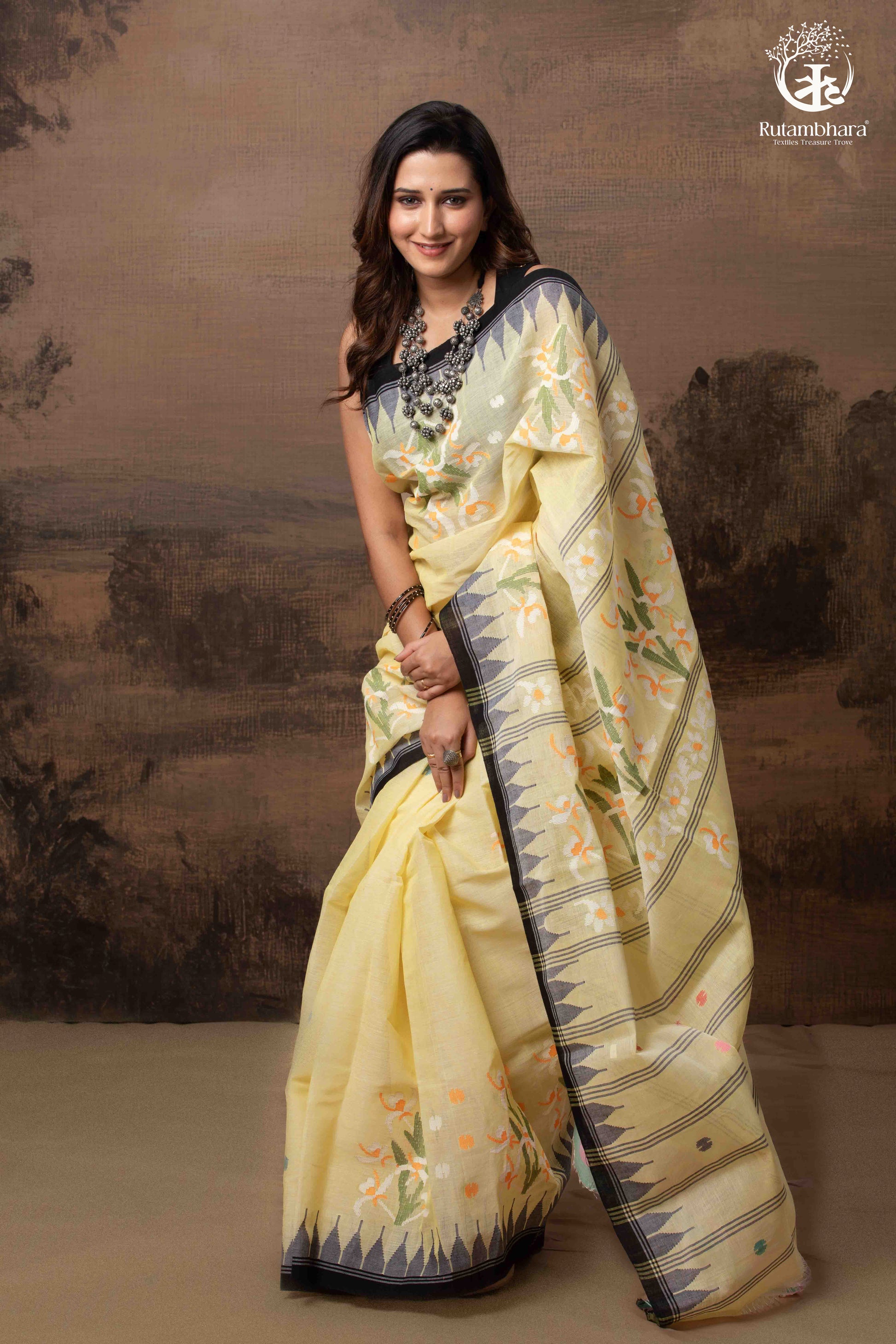Woman wearing a light yellow saree with a dark border against a scenic background