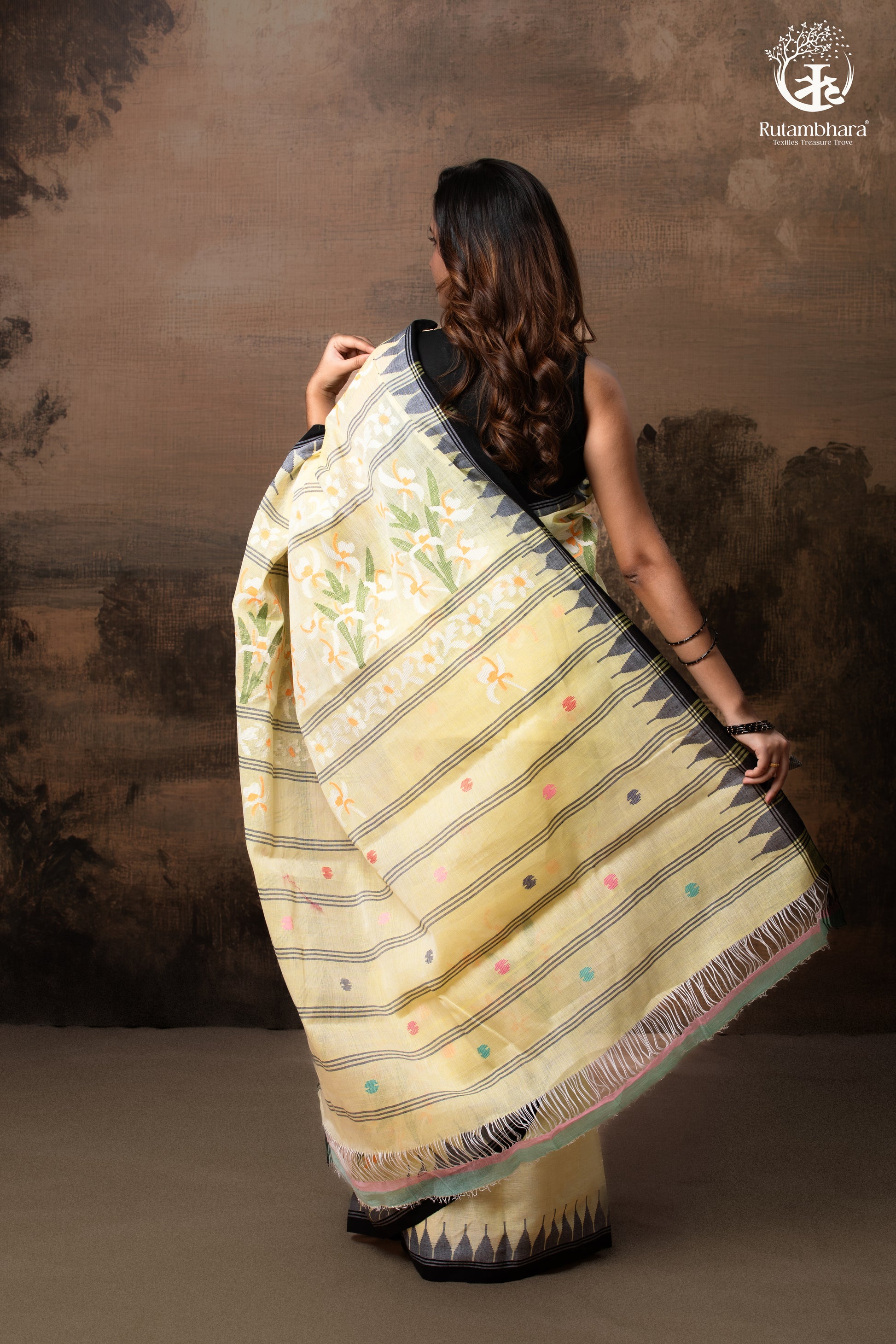 Woman wearing a traditional saree with a floral pattern against a brown background - Pallu view