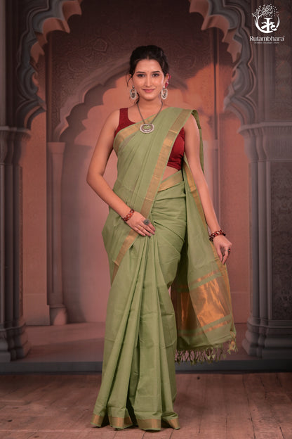 Woman in a green saree with a red blouse against an ornate architectural background