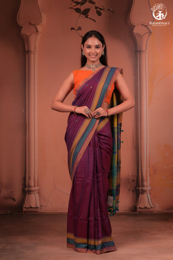 Woman in a traditional saree standing against an architectural background